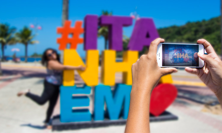 Pessoa tirando foto no letreiro #Itanhaém